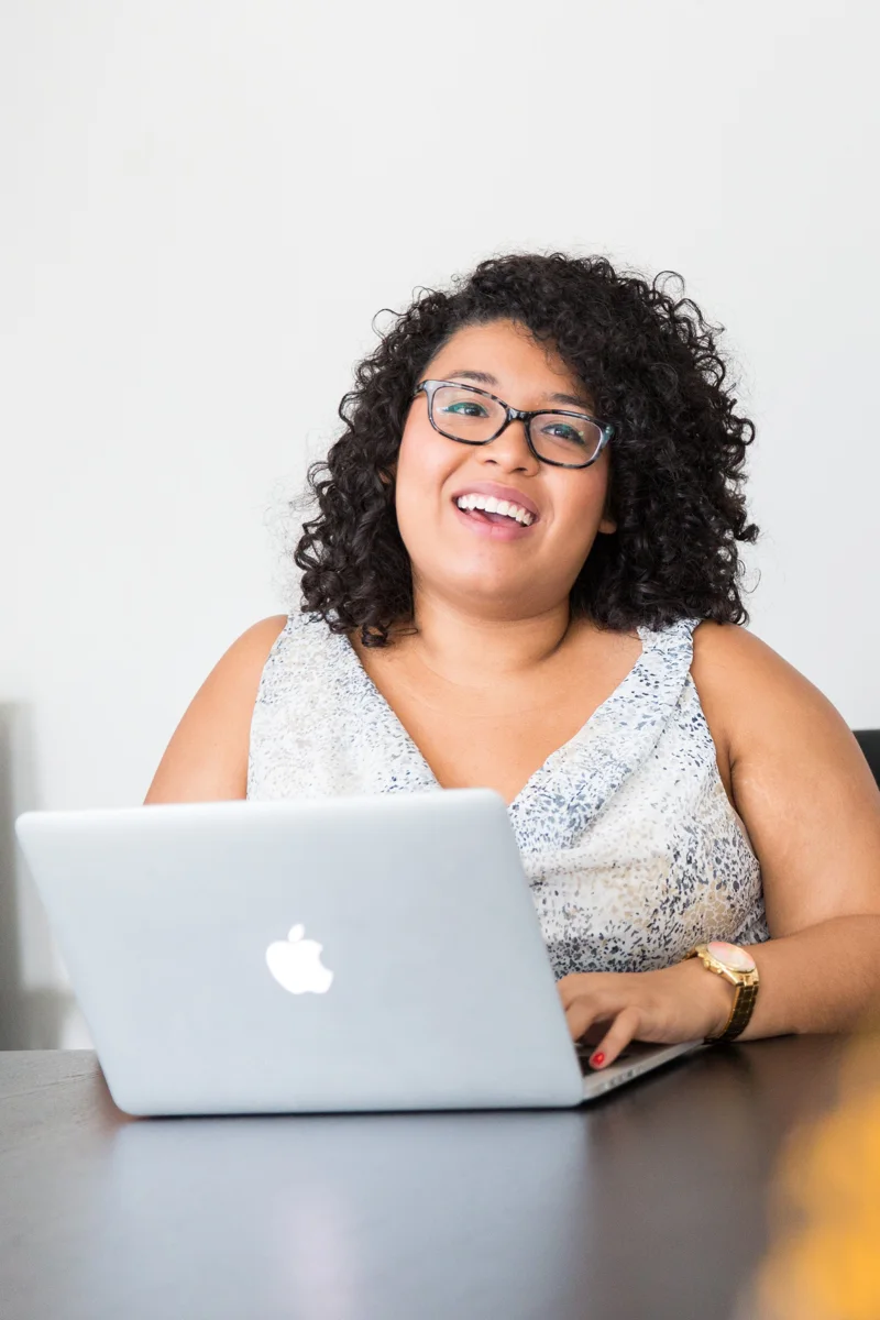 A professional smiling while working on a laptop